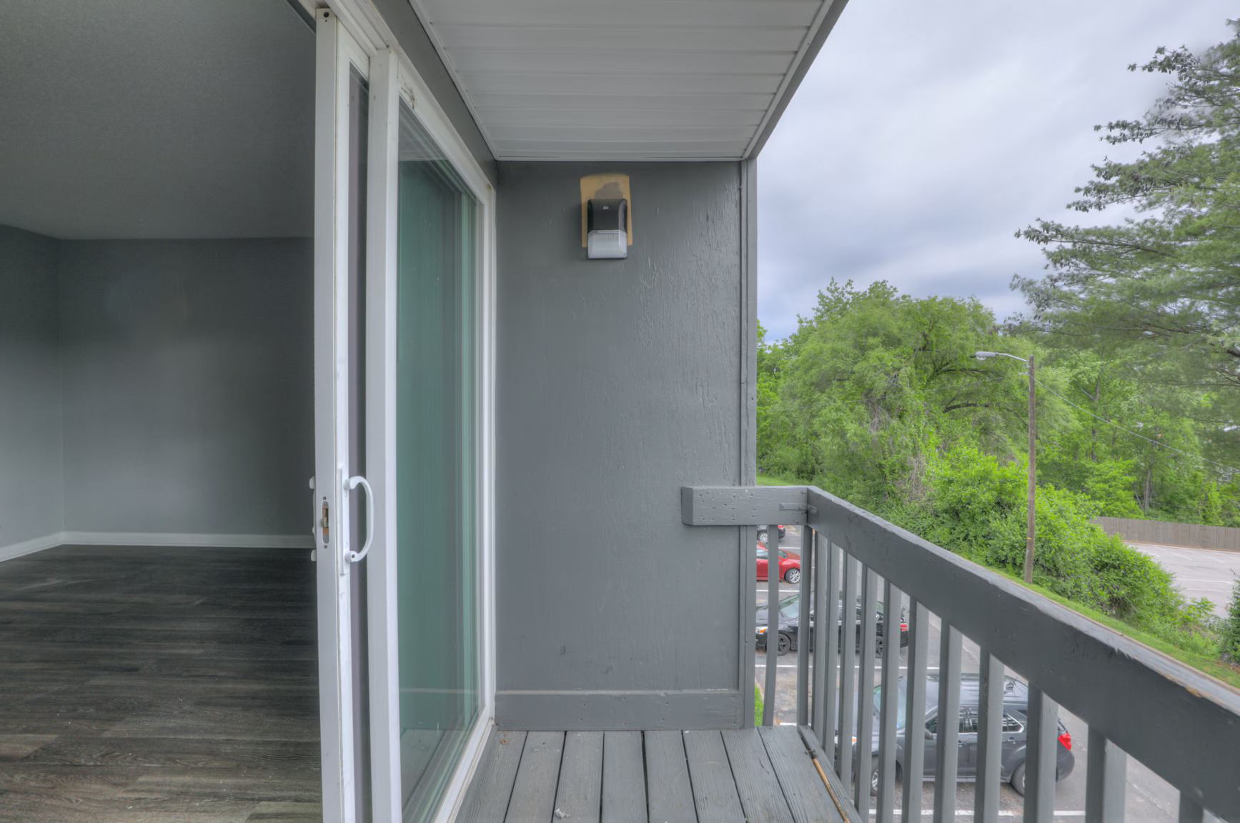 A balcony with a glass door leading to a grey deck.